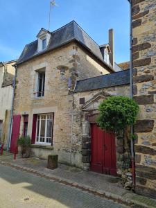 une vieille maison en pierre avec une porte rouge dans une rue dans l'établissement Le Coeur de Fresnay, à Fresnay-sur-Sarthe