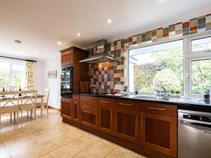 a kitchen with wooden cabinets and a large window at Longhouse Bungalow in Polzeath