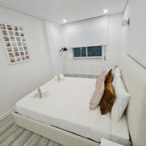 um quarto branco com uma grande cama branca e uma janela em S. Soares T3 Setúbal em Setúbal