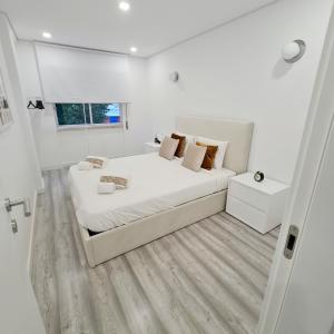 um quarto branco com uma cama grande e uma janela em S. Soares T3 Setúbal em Setúbal
