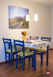 a blue dining room table with chairs and a painting at Ferienwohnung Glusavinahüsle in Vandans