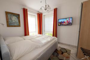 - un lit blanc dans une chambre dotée de rideaux orange dans l'établissement Schwalbenflug 1 Berlin, à Berlin