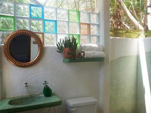 a bathroom with a sink and a mirror and a toilet at Una Posada Mas in Mazunte