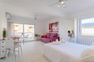 - une chambre blanche avec un lit blanc et un canapé rose dans l'établissement Very nice and modern studio front of the beach, à El Campello