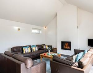 a living room with leather couches and a fireplace at Lerryn in Saint Minver