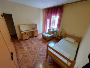 a bedroom with a bed and a desk and a window at Hills Apartment in Niš