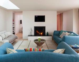 a living room with blue couches and a fireplace at Downalong in Polzeath