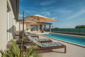 a group of lounge chairs with an umbrella next to a swimming pool at Villa Cristalines in Smoljanci