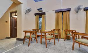 ウダイプールにあるTreebo Trend The Regal House - Near Fateh Sagar Lakeの木製の椅子とテーブル、窓が備わる客室です。