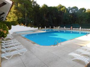 une grande piscine entourée de chaises longues blanches dans l'établissement El capricho para todos, à Arenas de San Pedro