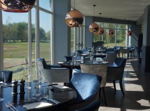 uma sala de jantar com mesas, cadeiras e janelas em Formby Hall Golf Resort & Spa em Southport