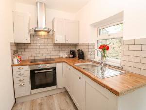 a kitchen with white cabinets and a sink and a window at Bracken Cottage in Bishop Auckland