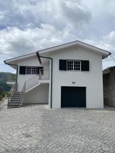 une maison blanche avec un garage et des escaliers. dans l'établissement Cantinho Verde T3, à Gerês
