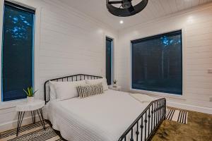 a bedroom with a bed and two windows at "The Barndo" 4BR Luxury Cabin, Hot Tub, Fire Pit, Bunks, Arcades, Playhouse! in Broken Bow