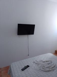 a bed with a television and a remote control on it at Pousada bandeirantes in Ilhéus