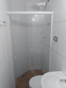 a white bathroom with a toilet and a shower at Pousada bandeirantes in Ilhéus