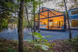 a house in the woods with a lot of windows at "The Barndo" 4BR Luxury Cabin, Hot Tub, Fire Pit, Bunks, Arcades, Playhouse! in Broken Bow