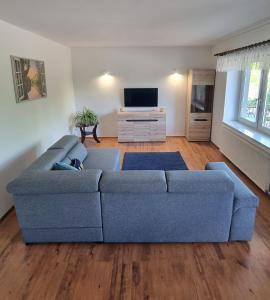 a living room with a blue couch and a tv at Apartament Riviera z widokiem na kanał Augustowski in Augustów