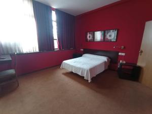 1 dormitorio con cama y pared roja en Hotel / Restaurante LA PEPA, en Avilés