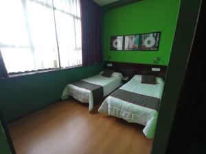 a room with two beds and green walls at Hotel / Restaurante LA PEPA in Avilés