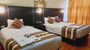 库斯科Hotel Mantas Cusco的一间酒店房间，有两张床，床上有毛巾