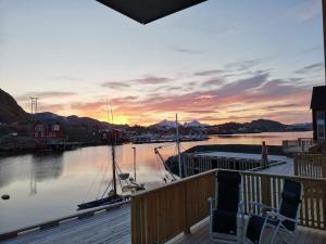 a sunset over a marina with two chairs on a deck at Karlotte's apartment in Ballstad