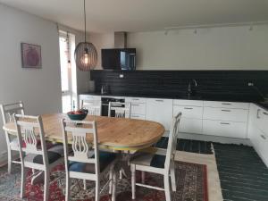 a kitchen with a wooden table and white cabinets at Karlotte's apartment in Ballstad