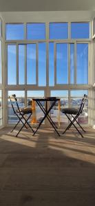 a table and two chairs in a large room with windows at GATU El Mirador de la Viña in Cádiz