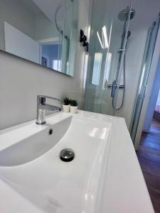 a white bathroom with a sink and a shower at GATU El Mirador de la Viña in Cádiz