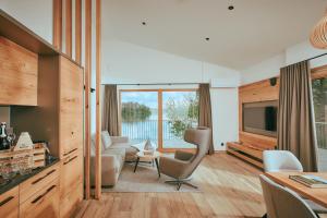 a living room with a television and a couch and chairs at Chalet Resort Seenland in Steinberg