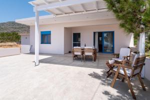 a patio with a table and chairs and a house at Sea view Pine house in Makry Gialos