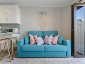 Cosy Seaview Apartment في سانتياغو ديل تيدي: أريكة زرقاء مع وسائد عليها في مطبخ