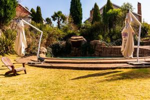 a garden with a bench and two closed umbrellas at Valley View dullstroom - check in at The Highlander Hotel in Dullstroom