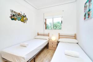 two beds in a room with white walls and a window at Espanhouse Rio Mar in Pilar de la Horadada +24 photos