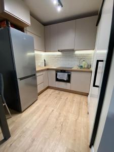 a kitchen with a stainless steel refrigerator and wooden floors at Cute house in Kretowiny