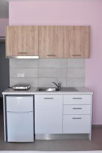una cocina con armarios blancos y fregadero en Giorgos-Fenia Apartments, en Paralia Katerinis