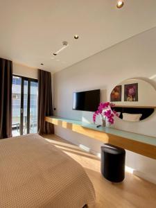 ein Hotelzimmer mit einem Bett und einem Flachbild-TV in der Unterkunft Hotel Nertili in Sarandë