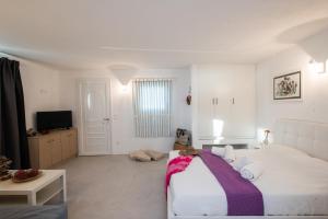a white bedroom with a bed and a tv at mykonos 1001 in Agios Stefanos