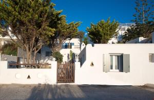 a white house with a gate and trees at mykonos 1001 in Agios Stefanos