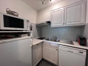 eine Küche mit weißen Schränken, einer Spüle und einer Mikrowelle in der Unterkunft Crystal 15 - 2 pieces centre in La Clusaz