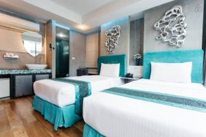 two beds in a hotel room with a bathroom at Blutique Hotel in Bangkok