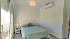 a white bedroom with a bed with blue pillows at La Fontanilla Place in Conil de la Frontera +18 photos