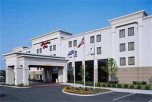 a white building with two flags in front of it at Hampton Inn Linden in Linden