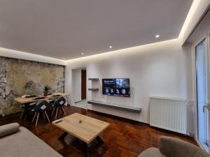Una sala de estar con una mesa y un televisor en la pared. en Arman Group Lannister, en Atenas