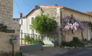 una casa con una corona de flores púrpuras. en La Maison Mûrier, en Chef-Boutonne