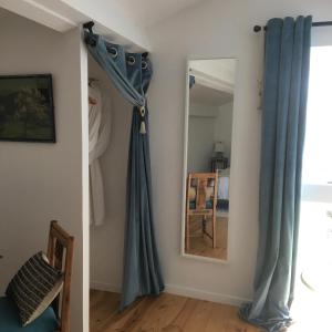 Habitación con cortinas azules y espejo. en La Maison Mûrier, en Chef-Boutonne