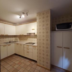 an empty kitchen with white cabinets and a microwave at Cesa Monica in Canazei