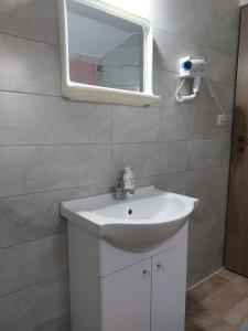 La salle de bains est pourvue d'un lavabo blanc et d'un miroir. dans l'établissement Cabana Rustica Georgeta, à Zărneşti
