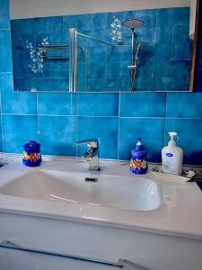 een wastafel met blauwe tegels op de muur bij La Fontanella Apartment in Taormina