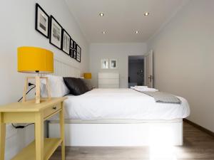 1 dormitorio con cama blanca y escritorio amarillo en Precioso piso nuevo dentro del recinto amurallado en Lugo